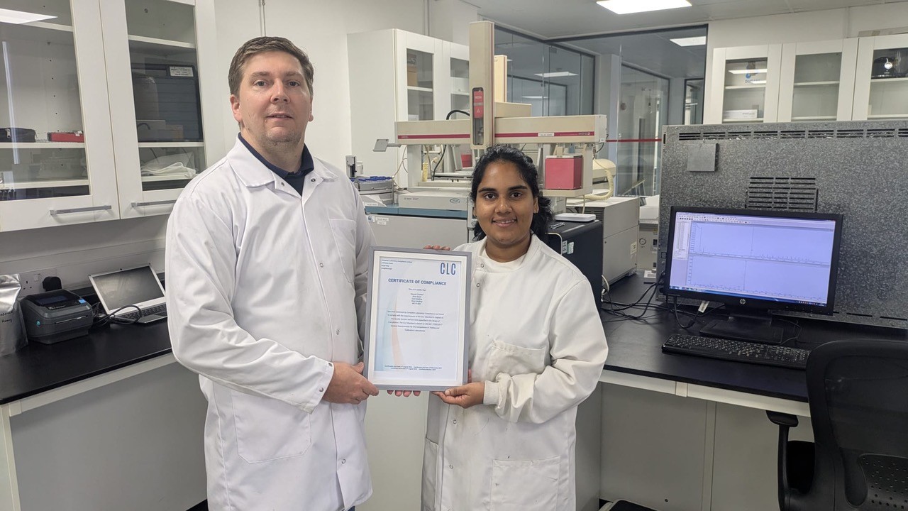 NEXTLab team members holding the CLC Certificate of Compliance in the laboratory
